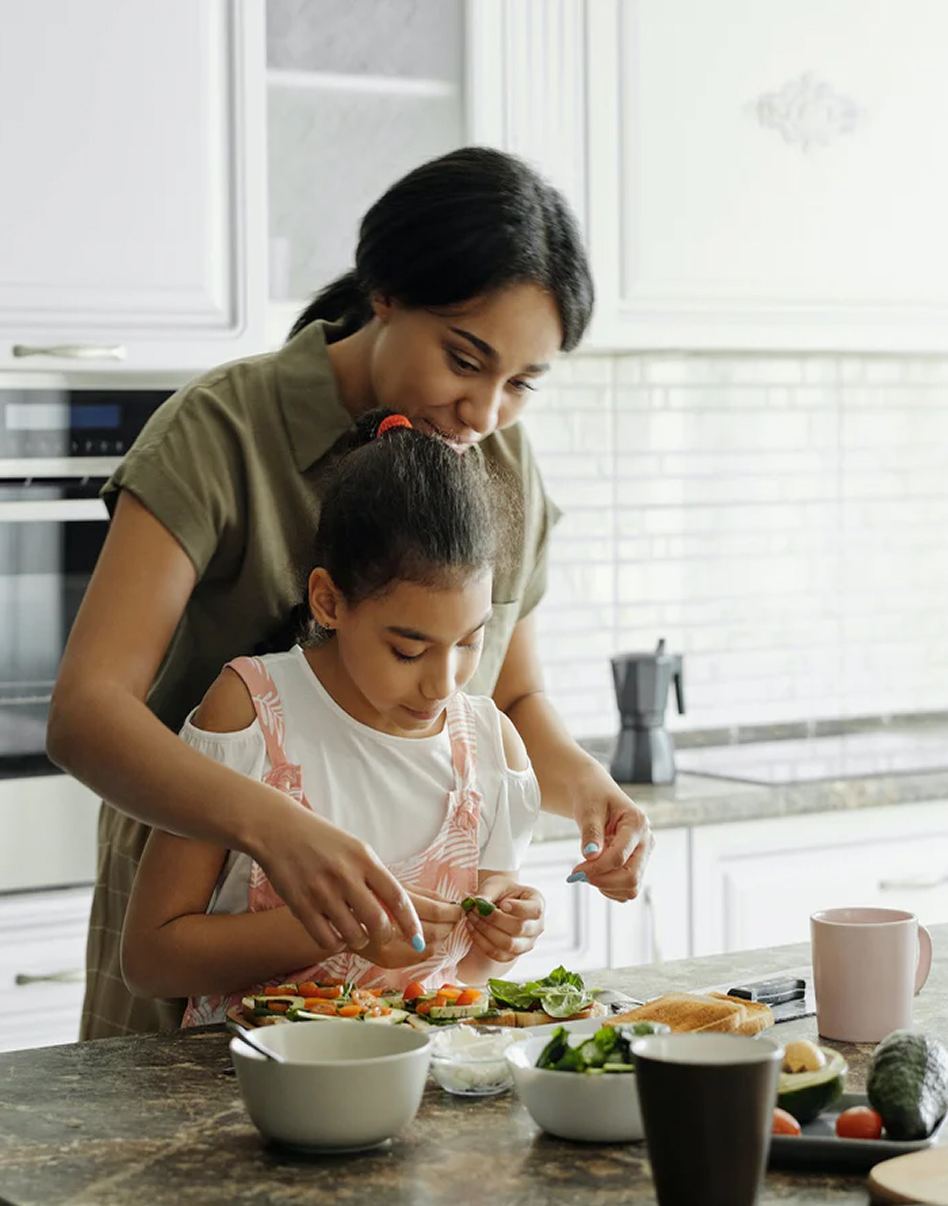 A mother and daughter preparing food together in a bright kitchen